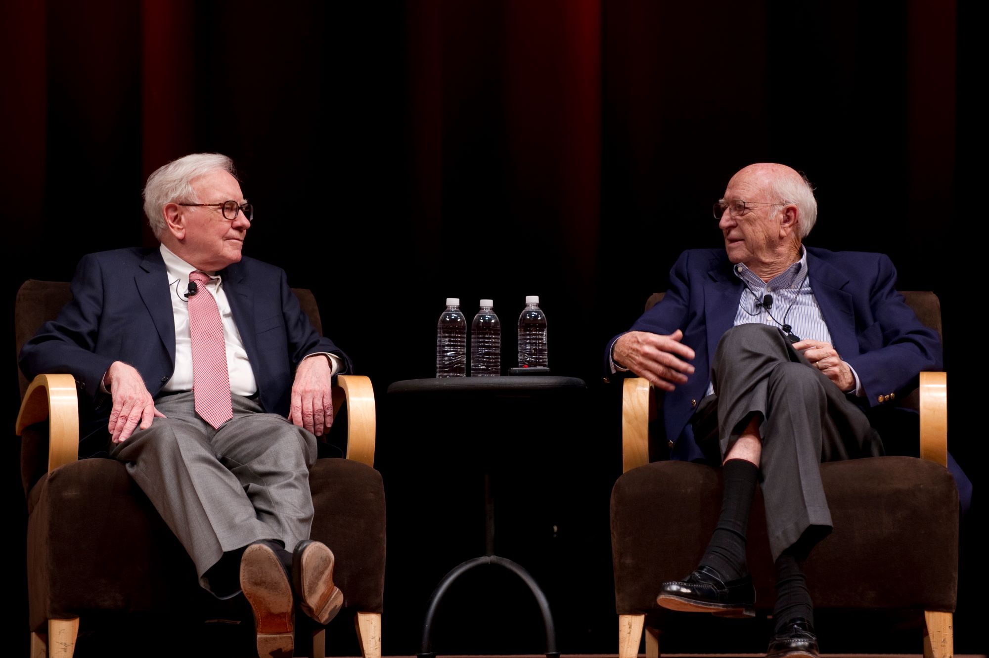 Warren Buffett and Bill Gates Sr. sit on a stage talking at the Gates Foundation Annual Employee Meeting.