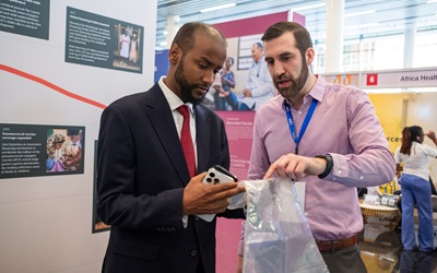 Hussain Aleaziz, a staff member of the Gates Foundation, chats with conference attendee Dr. Mohamed Hassan Mohamed, Deputy Minister of Health & Social Welfare of the Federal Government of Somalia (FGS) and Member of the Federal Parliament, as they walk through and interact with the Future of Health exhibit at the Africa Health Agenda International Conference (AHAIC), held at the Kigali Convention Center in Kigali, Rwanda on March 4, 2025. The exhibit showcases groundbreaking innovations that are currently saving lives and shaping the future of child health.