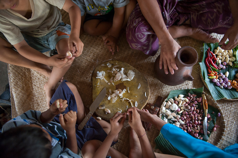 Family eating on a woven mat.