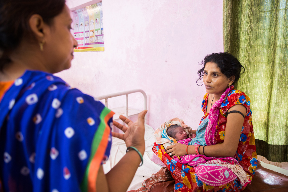 Sanno, 26, interacts with the doctor and staff nurse as she cradles her newborn at the community health center (CHC) in Achalganj, Unnao District, Uttar Pradesh, India.