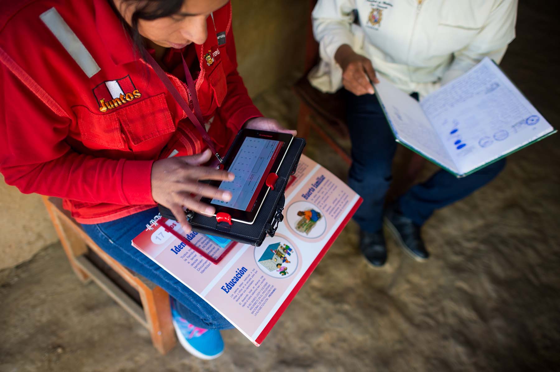 Picture of health care workers use a tablet to collect health and development data while speaking to a mother about her son during a check-in visit. (Sogobamba, Peru)